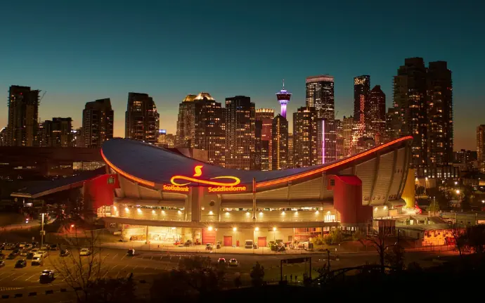 a large building with a lit up sign in front of a city skyline